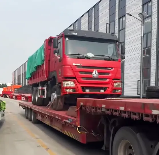Heavy duty low bed semi trailer transporting HOWO dump truck